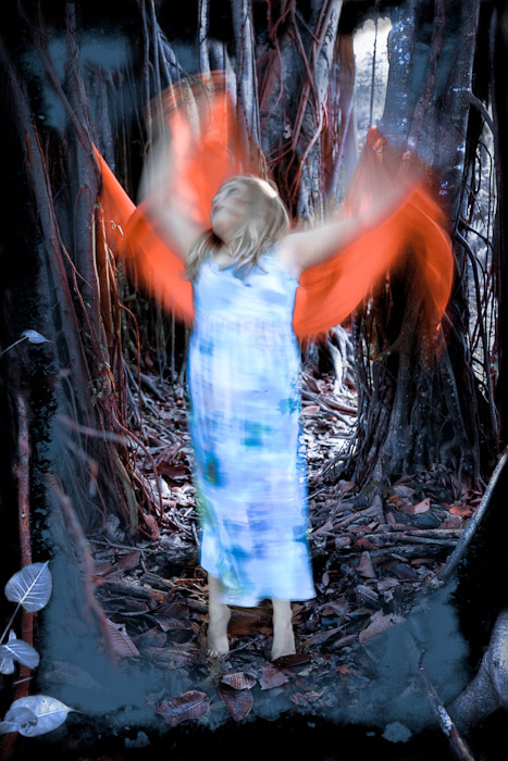 Figure raising bright orange fabric between mangrove trunks