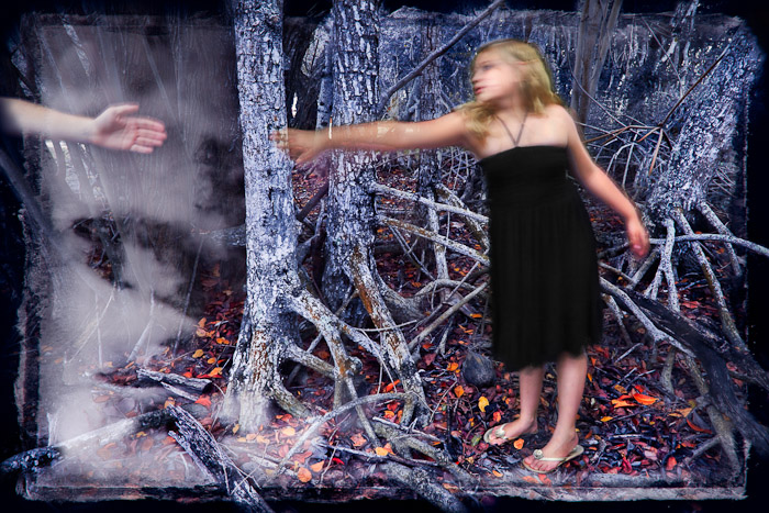 Figure in a dark dress reaching toward a hand among mangrove roots