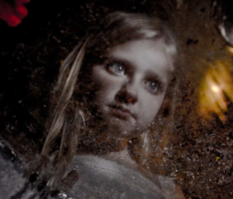 Close portrait of Eric’s daughter emerging from shadow and textured reflections