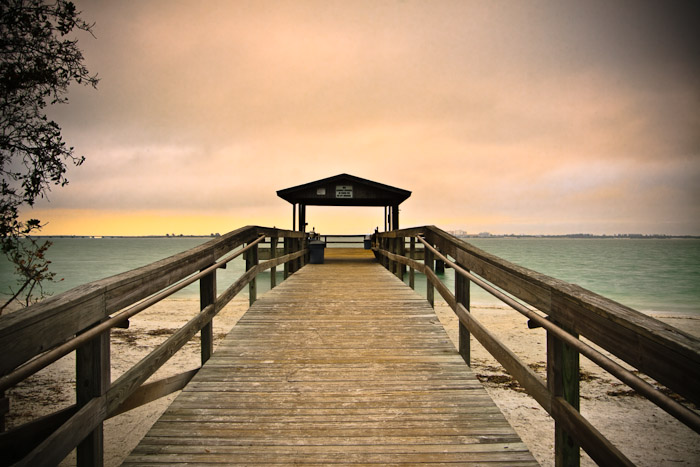 Wooden walkway leading toward a covered pier over open water